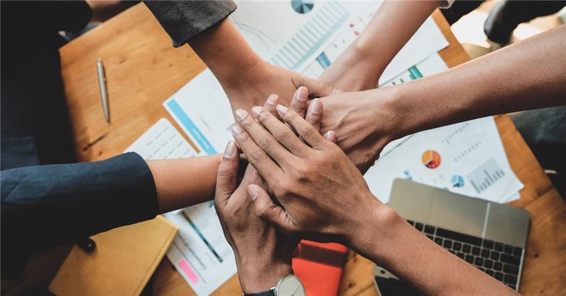 Several people placing their hands over documents 