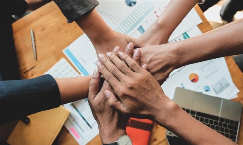 Several people placing their hands over documents 